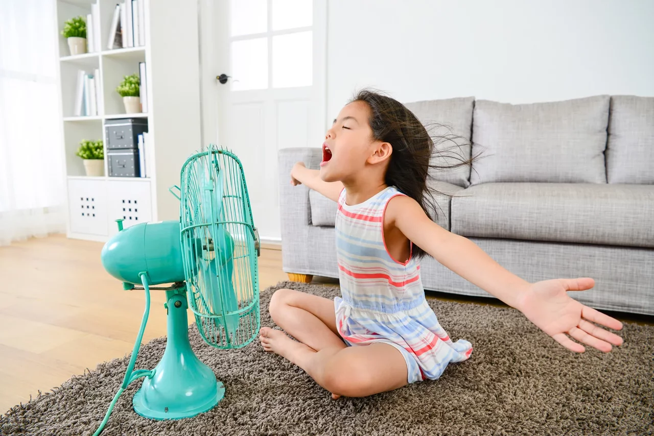 Kind sitzt vor Ventilator